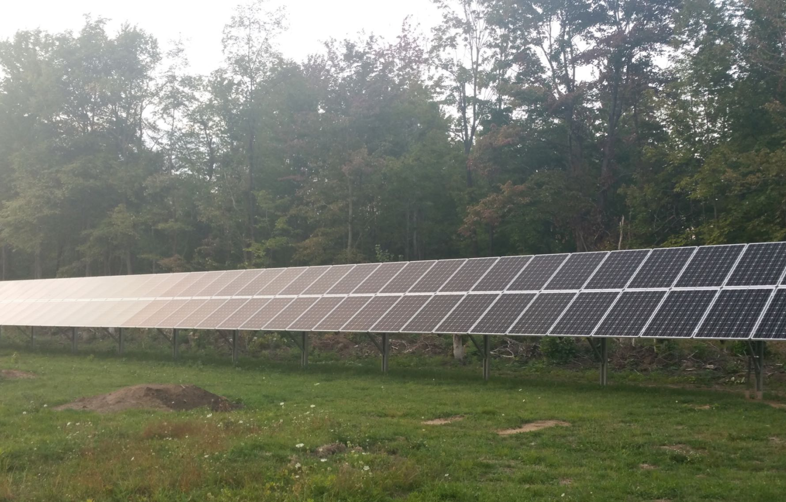 American Solar Partners - Ground mounted slanted solar panel installation in grass and soil